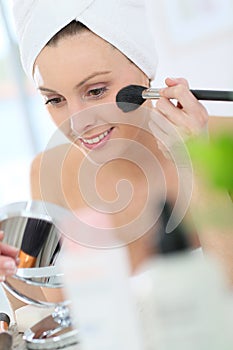 Young woman putting on makeup