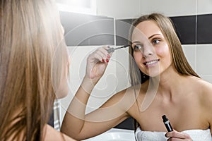 Young woman putting on mascara