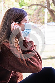 Young woman putting on a medical face mask to go outside and protect to covid-19