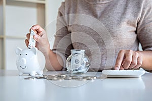 Young woman putting money into piggy bank planning growing saving to strategy and calculating with money box for future plan fund