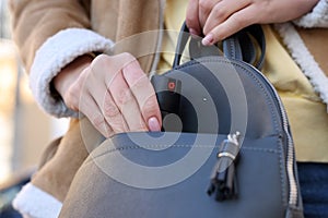 Young woman putting pepper spray into bag, closeup