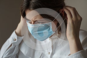 Young woman putting on a protective medical face mask. Protection from Coronavirus, covid-19