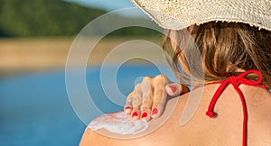 Young woman putting sun lotion on summer vacation