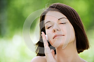 Young woman putting white cream on