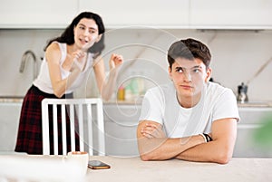 Young woman quarrels with young guy in kitchen
