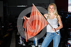 Young woman with race flag standing near car