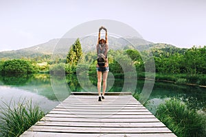 Young woman with raised arms up on the nature background.