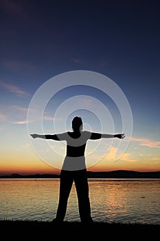 Young woman with raised hands standing at coast