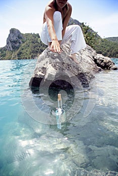 Young woman reaching for a message in a bottle