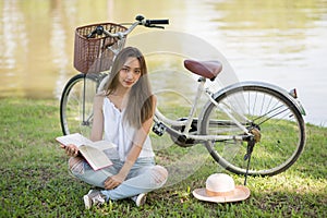 Young woman read book near bike at park