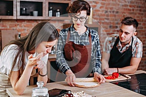 Young woman read the recipe at tablet pc while her friend cut in