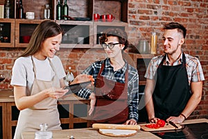 Young woman read the recipe at tablet pc to her friends preparin