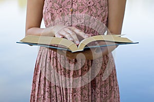 Young woman reading bible in natural park