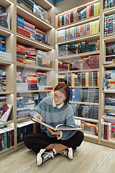 Young woman reading a book in a cozy bookstore