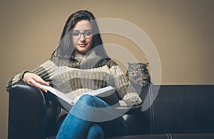 Young woman reading a book with curious cat