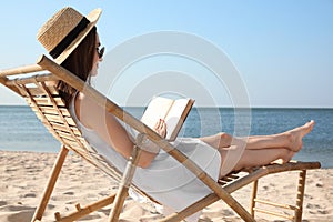 Young woman reading book in deck chair