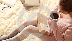 Young woman reading a book and drinking coffee