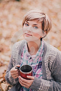 Young woman reading book and drinking tea in a forest