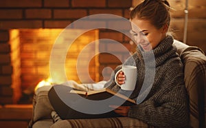 Young woman reading a book by the fireplace on a winter evenin