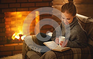 Young woman reading a book by the fireplace on a winter evenin