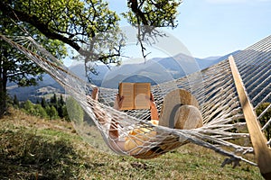 Young woman reading book in hammock outdoors on sunny day