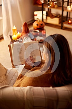 young woman reading book at home on halloween