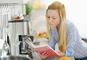 Young woman reading book in kitchen