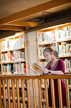 Young woman reading book in library