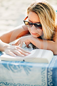 Young woman reading a book lying on the beach