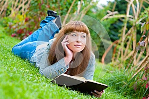 Young woman reading a book lying on the grass