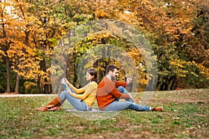 Young woman reading book and man using mobile phone while relaxi