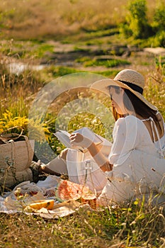 Young woman reading book in outdoor field. Reading and relaxation