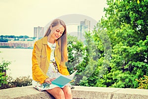 Young woman reading book outdoors in New York City