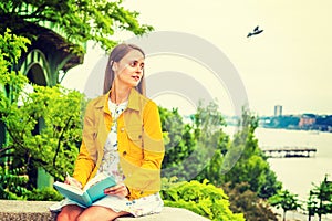 Young woman reading book outdoors in New York City
