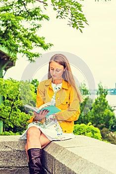 Young woman reading book outdoors in New York City
