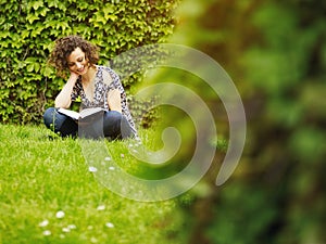 Mladá žena čítanie kniha v parku 