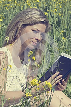 Young woman reading a book on the meadow