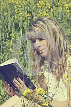 Young woman reading a book on the meadow