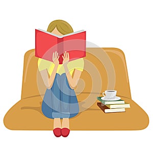 Young woman reading book sitting on sofa with a cup of tea on stack of books