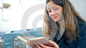 Young woman reading a book in subway platform