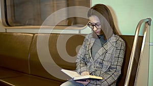 A young woman is reading a book in a subway train. Old subway car