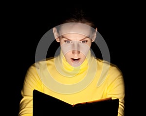 Young woman reading book surprised wondering