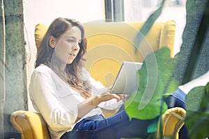 Young woman reading a book in a tablet device