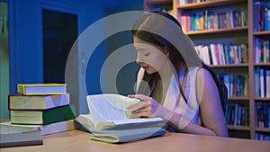 Young woman reading books and working in library for education