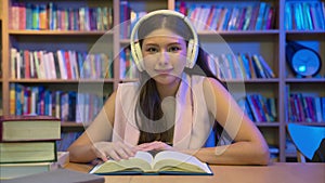 Young woman reading books and working in library for education