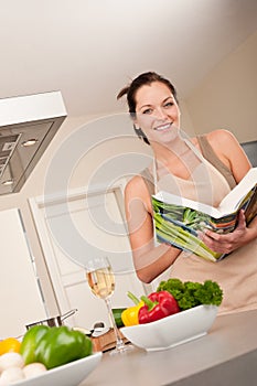 Young woman reading cookbook in the kitchen