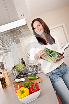 Young woman reading cookbook in the kitchen