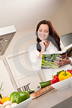 Young woman reading cookbook in the kitchen