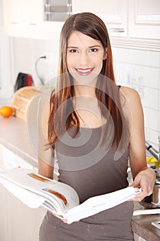 Young woman reading cookbook in the kitchen