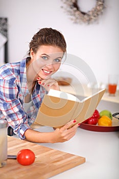 Young woman reading cookbook in the kitchen,